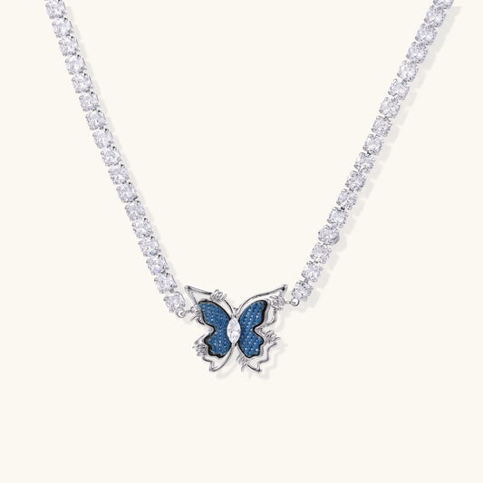 White gold plated tennis necklace with blue denim butterfly pendant and clear zirconia stones on cream background
