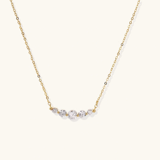 Delicate 14K gold-plated necklace with five graduated zirconia stones arranged in a curved arc on fine chain