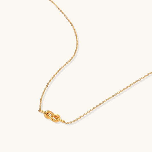 Dainty 18K gold plated necklace with infinity knot pendant on delicate chain against white background