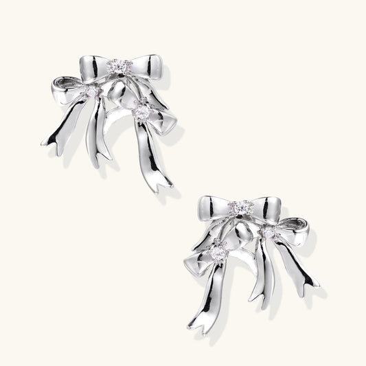Sculptural bow earrings in polished white gold plate with sparkling zirconia stones and flowing ribbon details