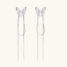 Pair of silver threader earrings with crystal butterfly tops and long chain drops on cream background.