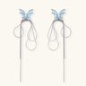 Long silver-tone earrings with powder blue enamel butterfly studs and flowing chain tassels on cream background