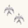 White gold-plated bird earrings with spread wings and oval zirconia center on cream background