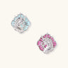 Silver unicorn stud earrings with pastel blue and pink enamel stones in sunburst prong settings on cream background