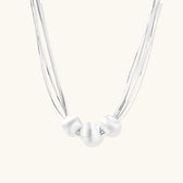 Sterling silver multi-strand necklace with three brushed round beads on cream background