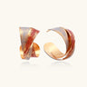 Sculptural gold-plated hoop earrings with diagonal purple and coral enamel stripes in twisted ribbon design