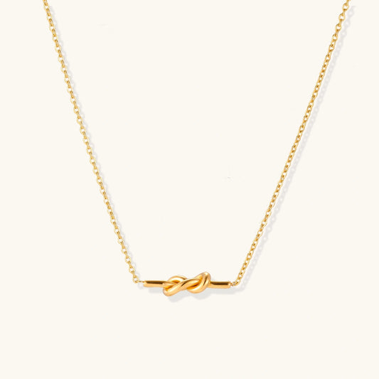 Dainty 18K gold plated necklace with infinity knot pendant on delicate chain against white background
