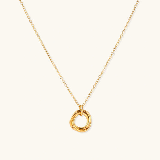 Delicate gold-plated necklace with three interlocking circle rings forming a minimalist knot pendant on cream background