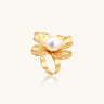 Gold-plated flower ring with textured petals and white cotton pearl center on cream background