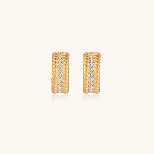 Textured gold huggie hoop earrings with raised ribbed rows creating dimensional sculptural design on cream background