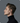 Man wearing a black turtleneck with a small device in his ear against a gray background